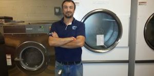 Jon Pell of National Laundry Equipment proudly stands next to the brand new Huebsch OPL laundry system now used by the Tennessee Titans!